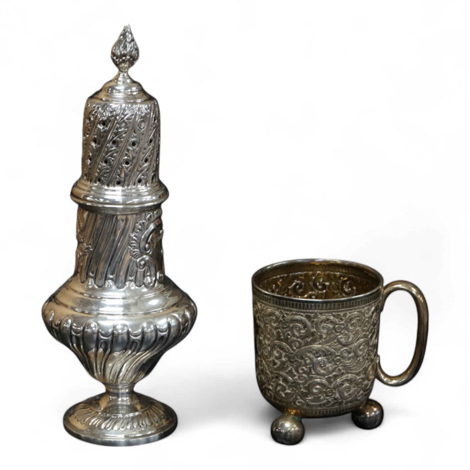 A Victorian embossed silver christening mug, on three ball feet, Martin, Hall & Co, London, 1874, height 85mm, together with a similar sugar caster, Lee & Wigful, Sheffield, 1899.
